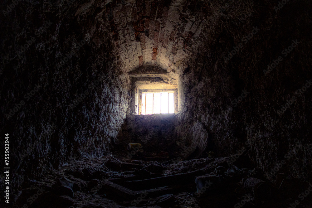Licht und Sonnenstrahlen fallen durch ein kleines weit entferntes vergittertes Kellerfenster
