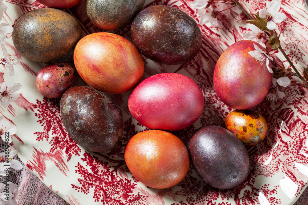 Eggs painted in different colors and covered with mother-of-pearl, and blossoming plum branches. Easter concept.