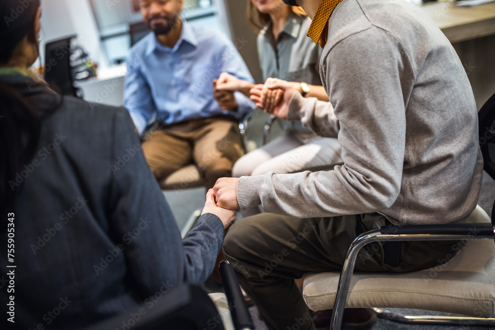 Fototapeta premium Group of people sitting in a circle holding hands and participate in a support meeting. Healthcare and medicine concept.