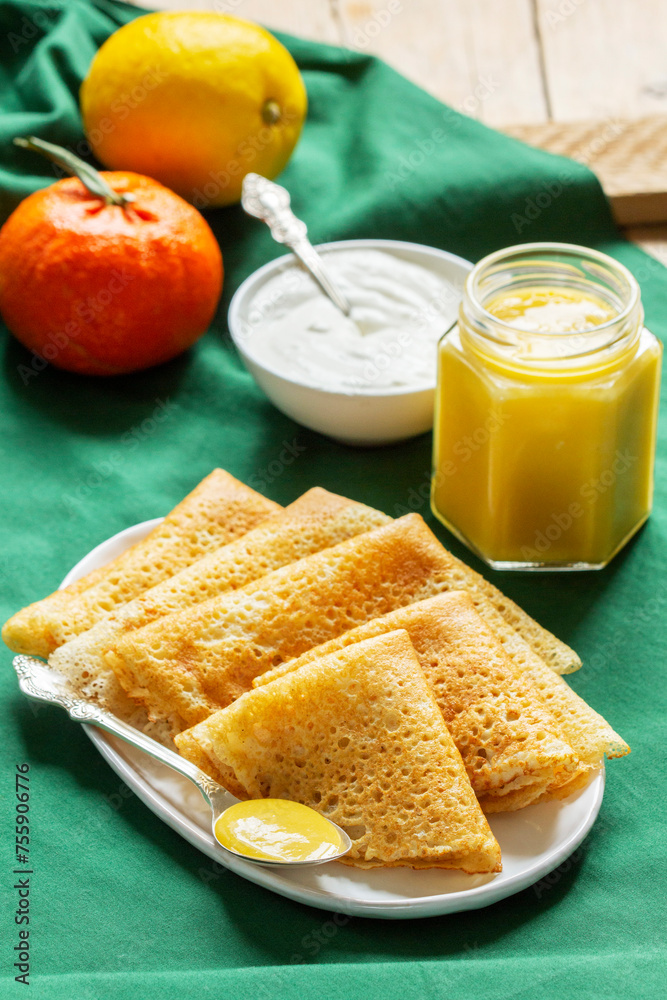 Pancakes served with fruit curd and sour cream, a traditional meal for Maslenitsa and Carnival.