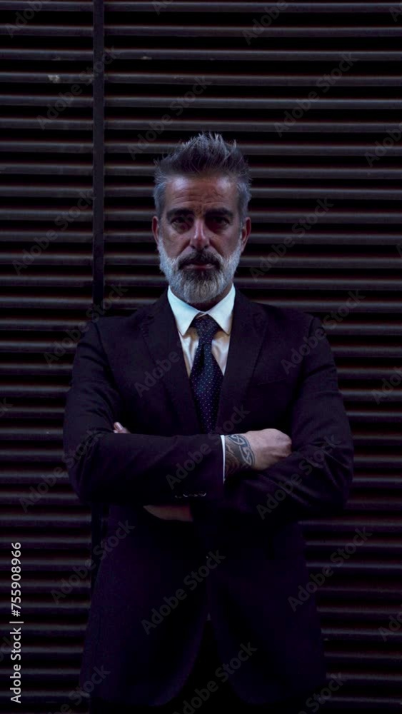 Experienced businessman stands with arms crossed, exuding confidence and authority. Stylish male with beard,cinematic danger red light playing across background, adding depth to scene. Vertical format Experienced businessman stands with arms crossed, exuding confidence and authority. Stylish male with beard,cinematic danger red light playing across background, adding depth to scene. Vertical format