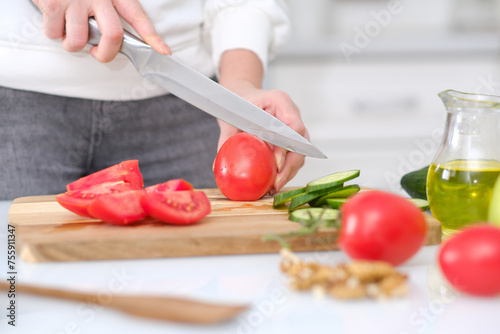 Woman cutting fresh tomatoes at table in a light kitchen  closeup