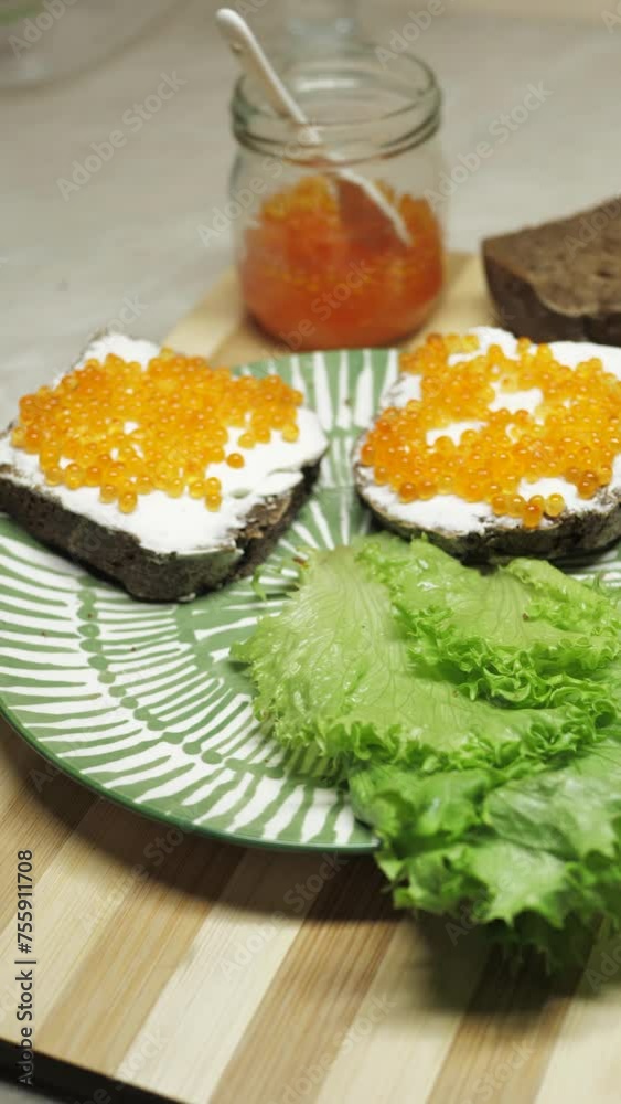Vertical screen hands take sandwiches with red salmon caviar from a plate for eating. Eating fish and fish products from the sea or river. Nutritious breakfast or snack