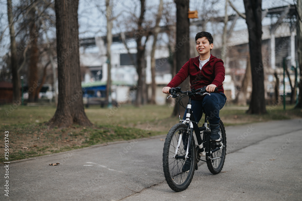A cheerful young boy riding his bicycle outdoors, enjoying the freedom and happiness of a carefree childhood in a green urban park.