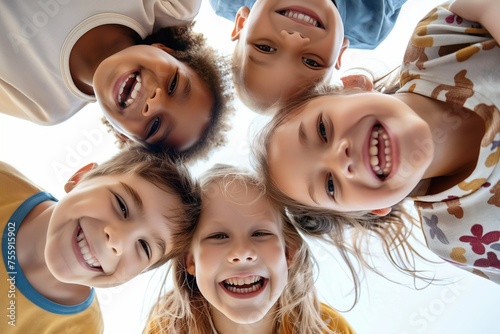 Happy smiling and cheerful children stand in a circle and look down at the camera, bottom view