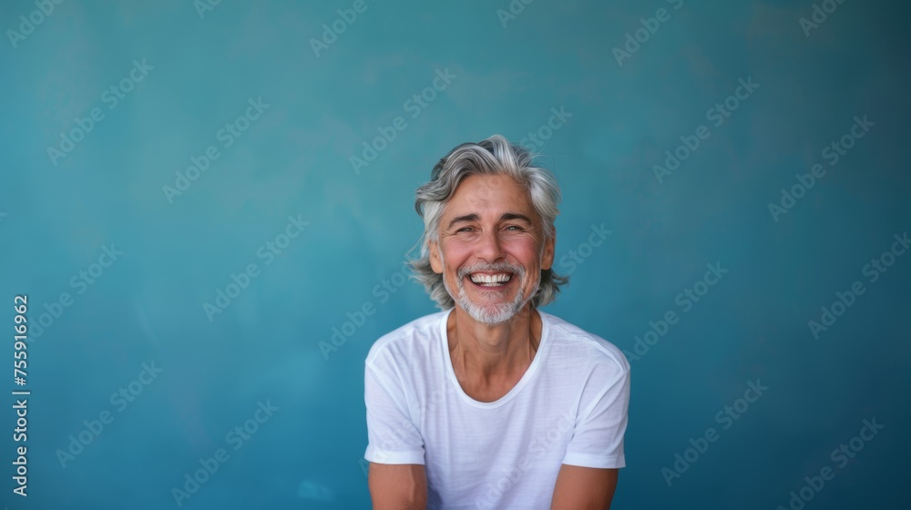 Fototapeta premium A middle-aged man with gray hair on a blue background with a pleasant smile. Health and beauty, healthy teeth.