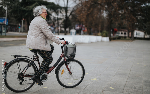 Mature woman enjoying a leisurely bike ride in a serene city park environment.