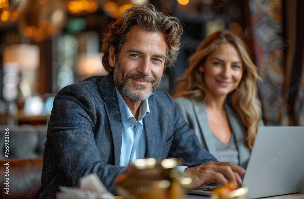 A man and a woman are sharing a laptop at a table, having fun A man and a woman are sharing a laptop at a table, having fun