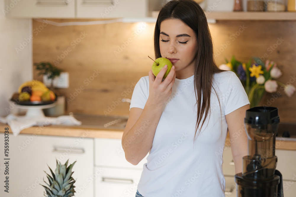 Young woman hold green apple in hand and sniffs it. Young woman hold green apple in hand and sniffs it.