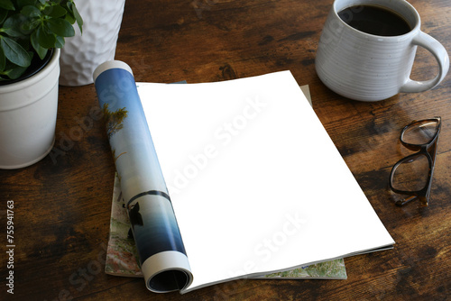 An open magazine laying on a table or desk with a white blank page for mock up.