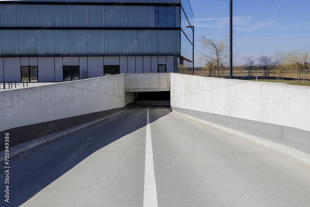 An underground car park entrance under a modern office building in Augsburg on a sunny spring day with a blue sky