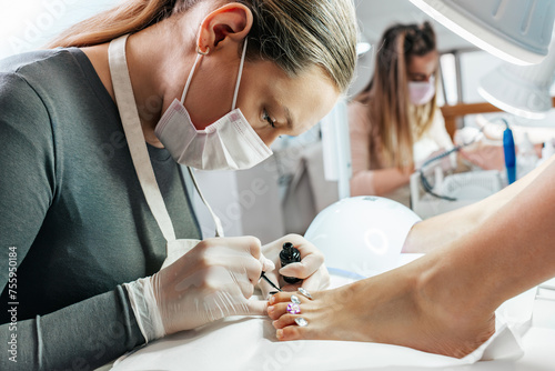 Group of professional podiatrists working in a modern nail beauty studio or spa. Satisfied clients relaxing and enjoying in a great foot and toenails treatment.