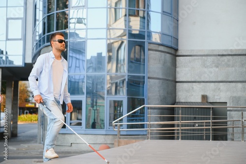 Blind Man Walking On Sidewalk Holding Stick.