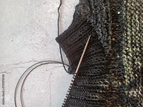 The process of knitting a jumper made of black and gray wool with sequins. High quality photo
