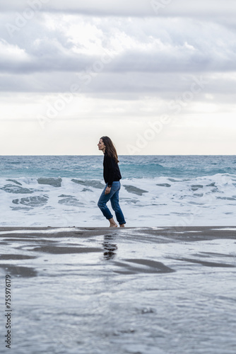 Adult woman walking carefree on a beach in winter.