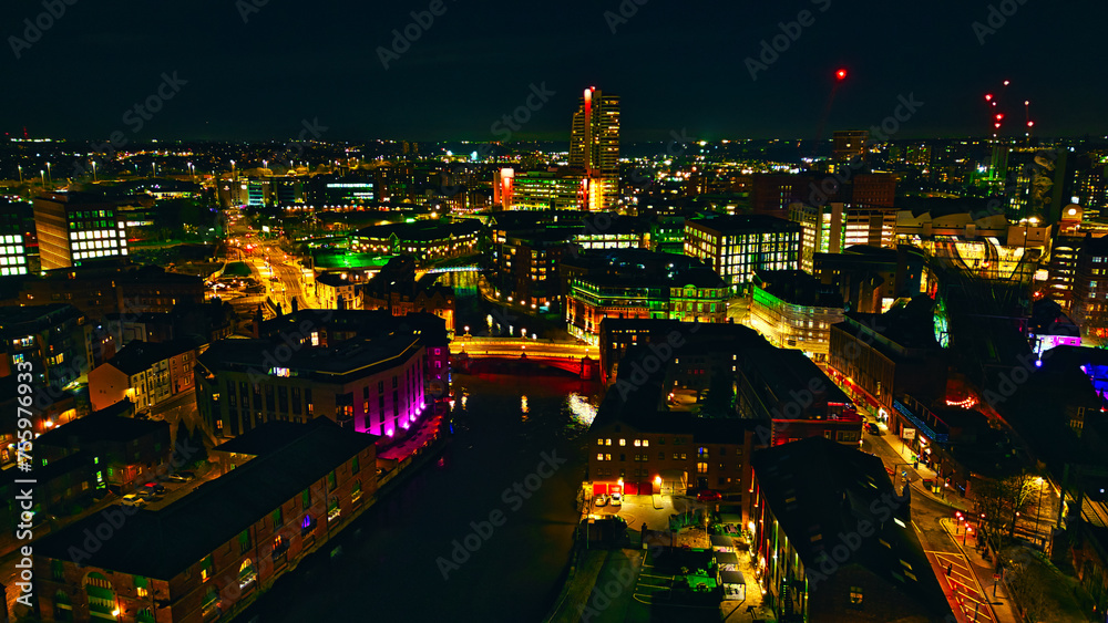 Aerial night view of a vibrant cityscape with illuminated buildings and streets in Leeds, UK.