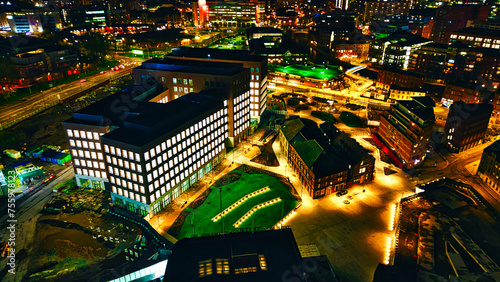Aerial night view of an illuminated urban landscape with buildings and streets in Leeds, UK.