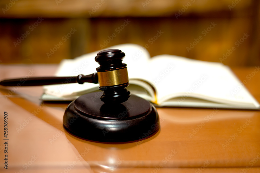 Judicial gavel HAMMER years on a backing on a wooden table against the background of an open magazine book out of focus, close-up, selective focus Judicial gavel HAMMER years on a backing on a wooden table against the background of an open magazine book out of focus, close-up, selective focus