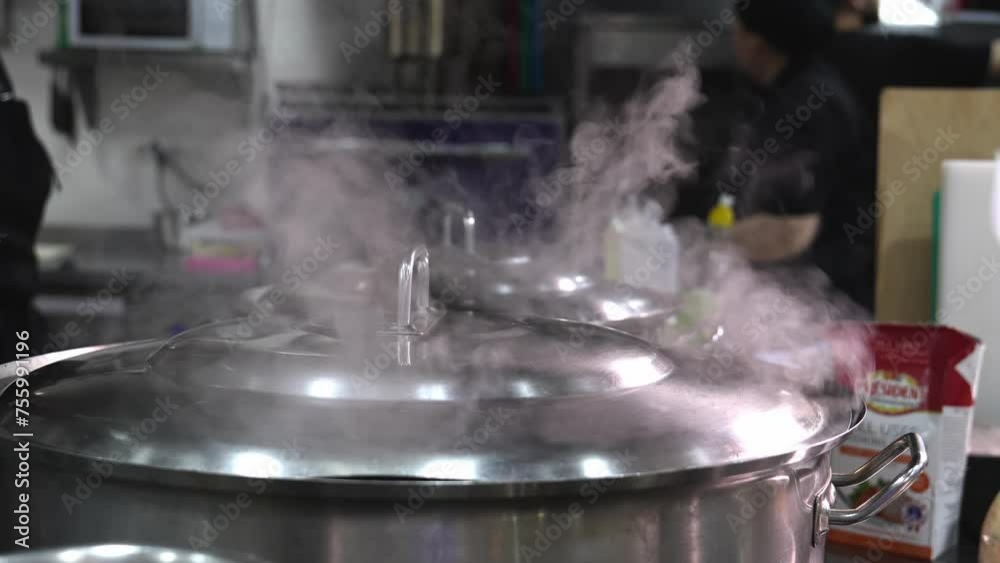 Food or soup is cooked in pots, water and steam evaporating from pot in restaurant kitchen. Blurred background, selective focus. Steaming over pots Food or soup is cooked in pots, water and steam evaporating from pot in restaurant kitchen. Blurred background, selective focus. Steaming over pots