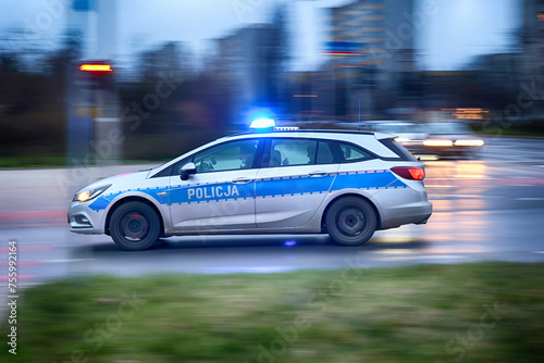 Radiowóz polskiej policji na sygnałach alarmowo szybko jedzie przez miasto na interwencję.
 photo