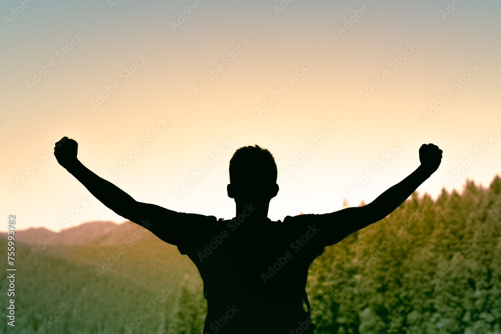 Strong, winning, confident victorious man on a mountain with fist up celebrating 