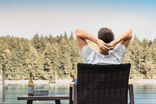 Happy carefree man sitting by a lake sitting back enjoying the beautiful nature view 