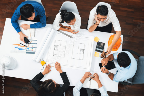 Top view banner of diverse group of civil engineer and client working together on architectural project, reviewing construction plan and building blueprint at meeting table. Prudent