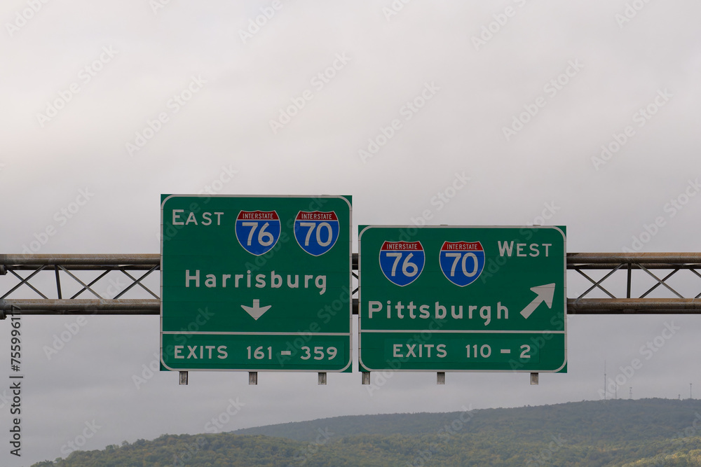 Exit signs for Interstate 76 and Interstate 70, East toward Harrisburg, Pennsylvania and West toward Pittsburgh, Pennsylvania