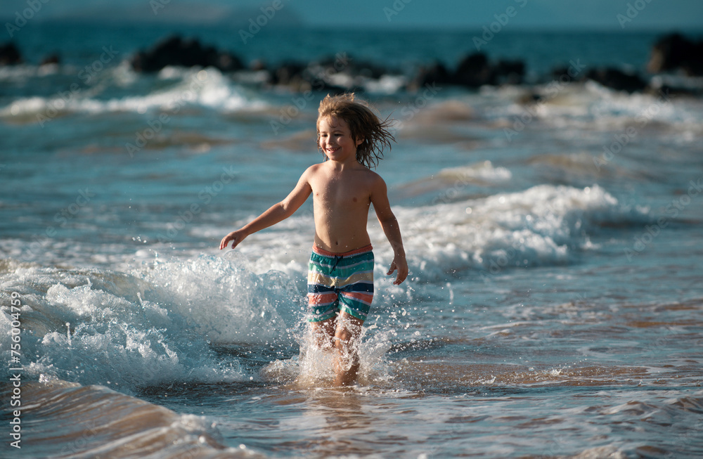 Child running through water close to shore along the sea beach. A boy runs along the sea coast. Rest of children on summer vacation.