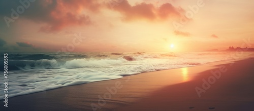 A hazy image of a beach at sunset with the sun peaking through the clouds, creating a mesmerizing atmosphere over the fluid water and natural landscape