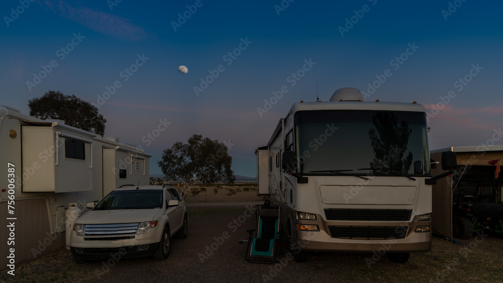 Camping at campsite in the Arizona desert with moon rising sky in background with tow vehicle