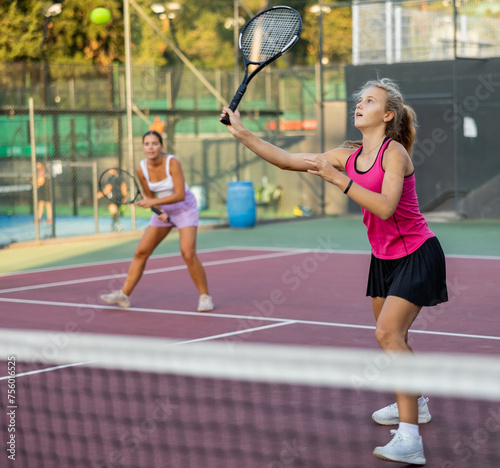 Young woman in skirt playing tennis on court. Racket sport training outdoors. © JackF