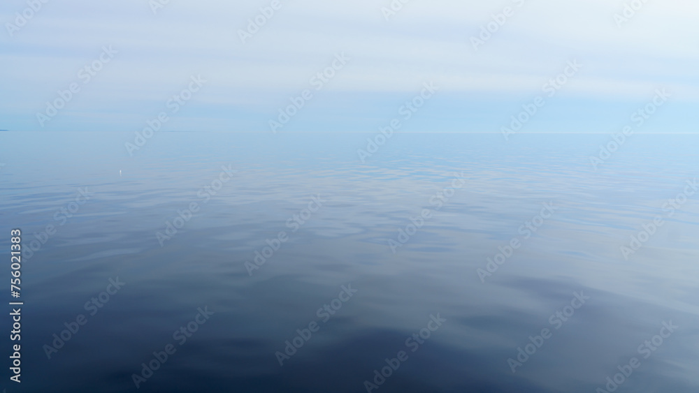Republic of Karelia, Russia, Lake Ladoga, Panoramic view of the lake surface during calm, mirrored water, cloudy sky, at daytime Republic of Karelia, Russia, Lake Ladoga, Panoramic view of the lake surface during calm, mirrored water, cloudy sky, at daytime