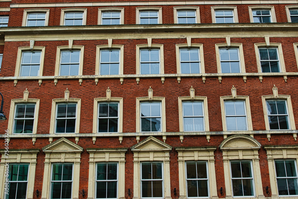 Facade of a classic red brick building with symmetrical windows against a clear sky in Leeds, UK.