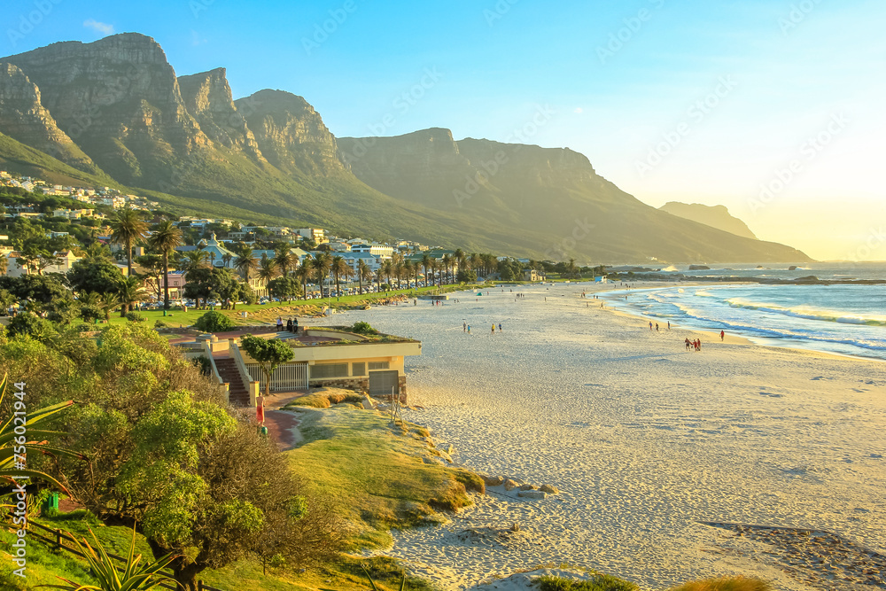 Fototapeta premium White long and spectacular beach of Camps Bay with Table Mountain National Park behind him in Cape Town, South Africa, Atlantic Ocean view. Shot taken at sunset.