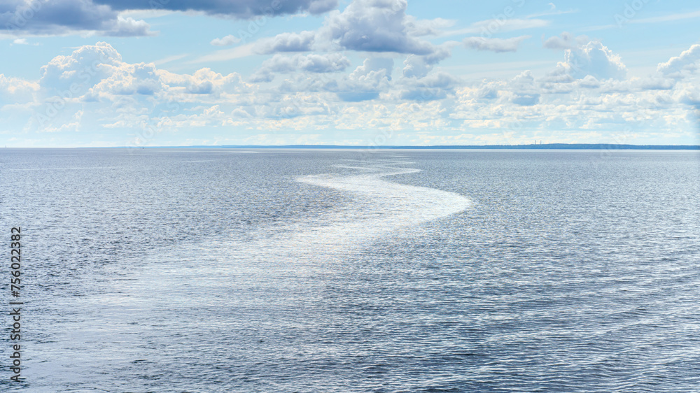 Obraz premium Republic of Karelia, Russia, Lake Ladoga, Panoramic view of the lake surface during calm, mirrored water with wake trail, cloudy sky, at daytime