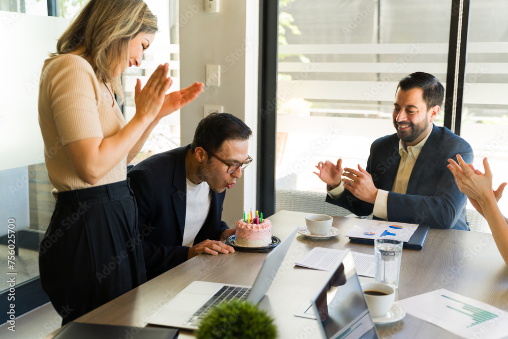 Businessman blowing off the candles of his birthday cake in a meeting room Businessman blowing off the candles of his birthday cake in a meeting room