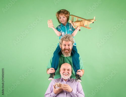 Boy son with father and grandfather with a toy airplane plays on isolated background. Family adventure, imagination, innovation and inspiration. Men in different ages. © Volodymyr