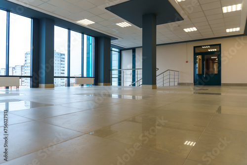 An empty spacious room of a modern office building with large windows. An empty hall with columns and a new renovation. Interior design. Suspended ceiling and square LED lamps.