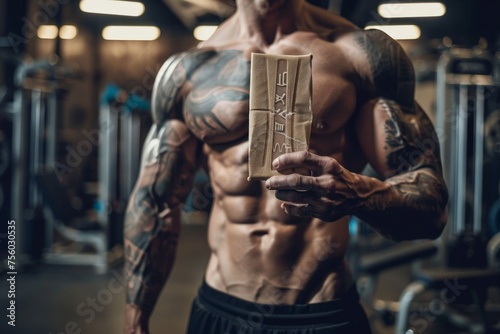 Muscular bodybuilder holding protein bar in gym © Aliaksandr Siamko