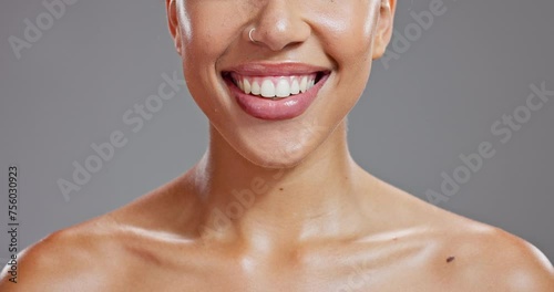 Beauty, smile and lips of woman in studio for wellness, dental health and hygiene for oral care. Dentist, smile and closeup of mouth of person with lip gloss, shine and cosmetics on gray background photo