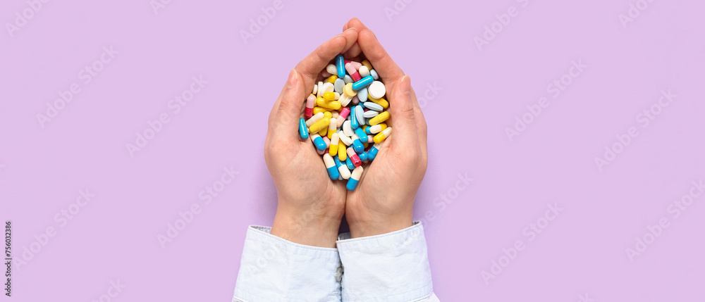 Female hands with many different pills on lilac background Female hands with many different pills on lilac background