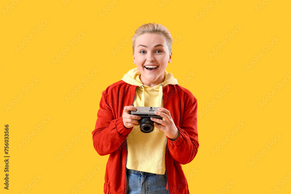 Happy young woman with photo camera on yellow background Happy young woman with photo camera on yellow background