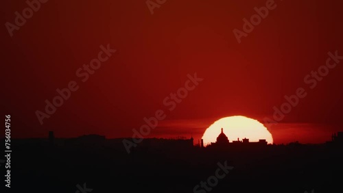 Wallpaper Mural A dramatic red sunset where the sun descends in perfect alignment behind a distinct dome silhouette, casting a fiery glow over the landscape. Torontodigital.ca