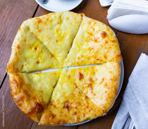 Delicious dish of Georgian cuisine is khachapuri Iveria with suluguni cheese and cut into pieces photo