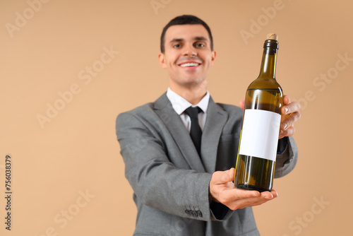 Young sommelier with bottle...