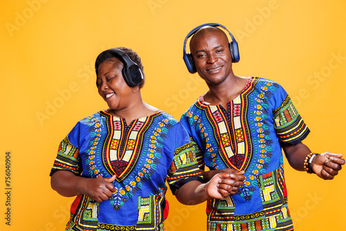 Happy black man and woman couple enjoying music in headphones and imagining to play guitar. Cheerful african american biyfriend and girlfriend wearing wireless headphones
