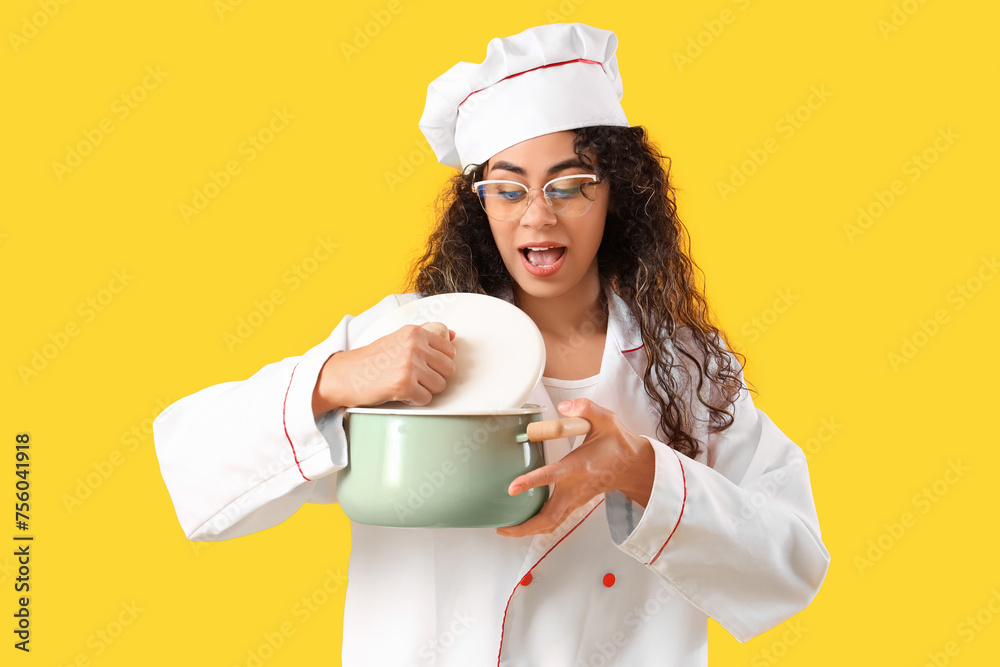 Female African-American chef in eyeglasses with cooking pot on yellow background Female African-American chef in eyeglasses with cooking pot on yellow background