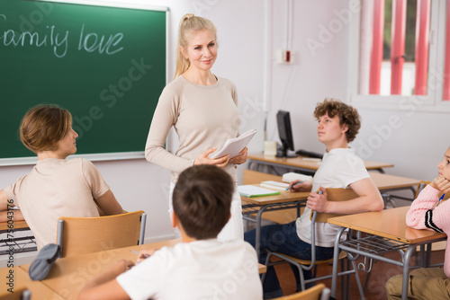 Portrait of young attractive female teacher giving lesson to children in secondary school indoors