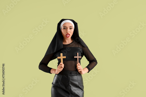 Sexy nun with crosses showing tongue on green background photo